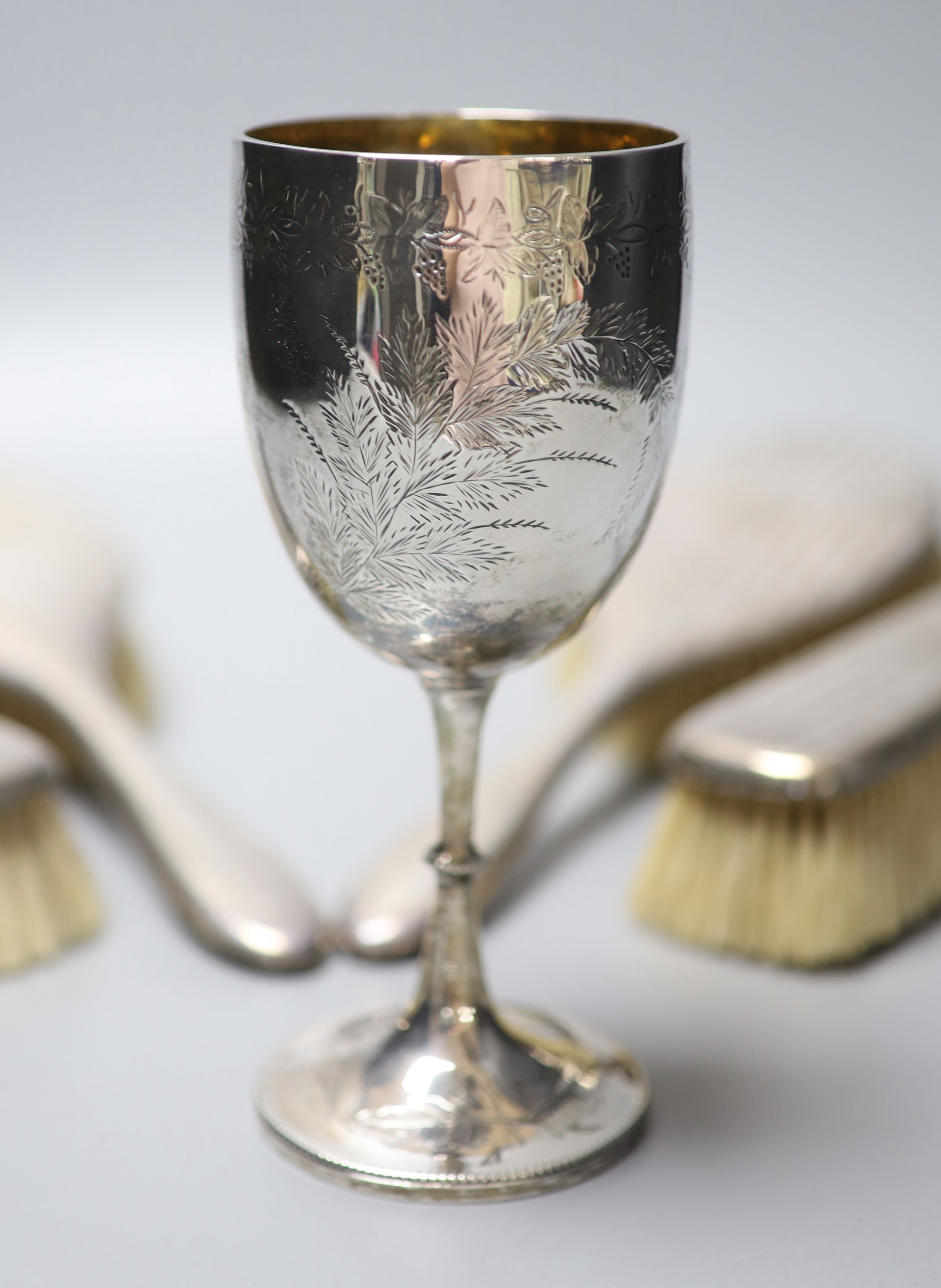 A Victorian engraved silver goblet, London, 1875, 6.3cm, a pair of silver sugar tongs and four silver mounted brushes.